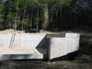 Looking East at lower level plumbing; rebars in top and bottom of walls; anti-solar tree cut to size by Nature!