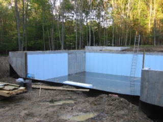 Slab poured, blue foam insulation, excavation filled in on West side on top of dimpled drainage wrap