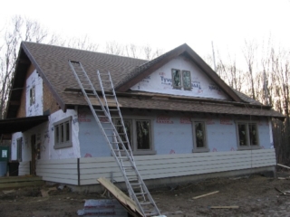 Looking Southwest; windows installed and trimmed on the first floor; roof shingled; clapboards hung
