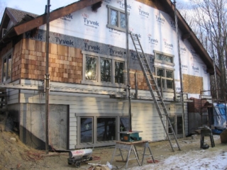 Looking Southeast; more cedar shingles, complete window trim and a start on the chimney